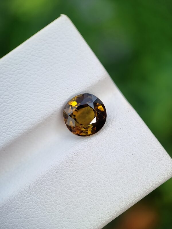 A photo of a loose faceted Epidote gemstone with a greenish-orange color and oval shape from Pakistan | 1.99 ct