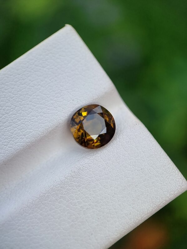 A photo of a loose faceted Epidote gemstone with a greenish-orange color and oval shape from Pakistan | 1.99 ct