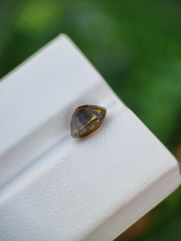 A photo of a loose faceted Epidote gemstone with a greenish-orange color and oval shape from Pakistan | 1.99 ct