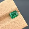 A clear photograph of a 0.94 carat natural emerald with an emerald cut and green color. The stone is from the Swat Valley and has visible internal inclusions.