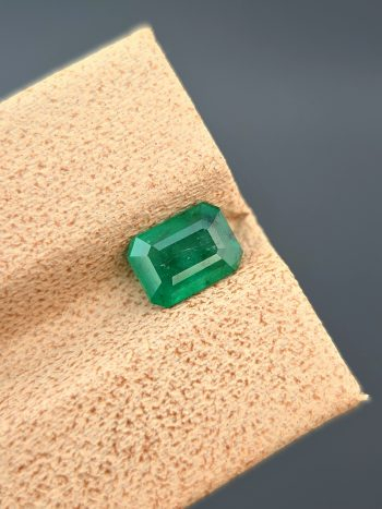 A clear photograph of a 0.94 carat natural emerald with an emerald cut and green color. The stone is from the Swat Valley and has visible internal inclusions.