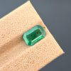A top-down, studio photograph of a 1.82 carat natural green emerald from the Swat Valley, Pakistan, in a classic emerald cut. The stone is transparent with visible inclusions.