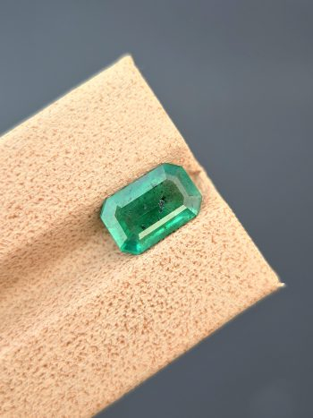 A top-down, studio photograph of a 1.82 carat natural green emerald from the Swat Valley, Pakistan, in a classic emerald cut. The stone is transparent with visible inclusions.