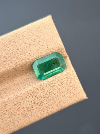 A top-down, studio photograph of a 1.82 carat natural green emerald from the Swat Valley, Pakistan, in a classic emerald cut. The stone is transparent with visible inclusions.