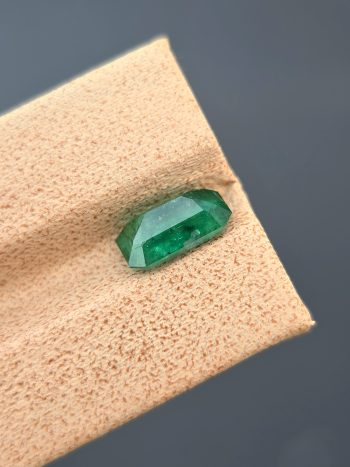 A top-down, studio photograph of a 1.82 carat natural green emerald from the Swat Valley, Pakistan, in a classic emerald cut. The stone is transparent with visible inclusions.