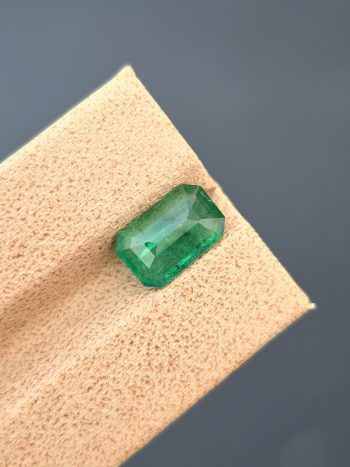 A top-down, studio photograph of a 1.82 carat natural green emerald from the Swat Valley, Pakistan, in a classic emerald cut. The stone is transparent with visible inclusions.
