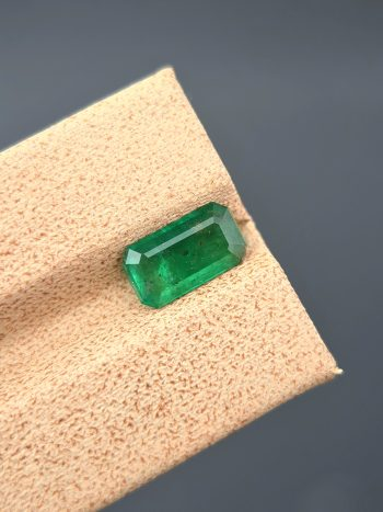 A crisp, detailed image of a 1.36 carat natural emerald from the Swat Valley, Pakistan. The stone is in the classic emerald cut and has a green color. Visible inclusions are present within the stone.