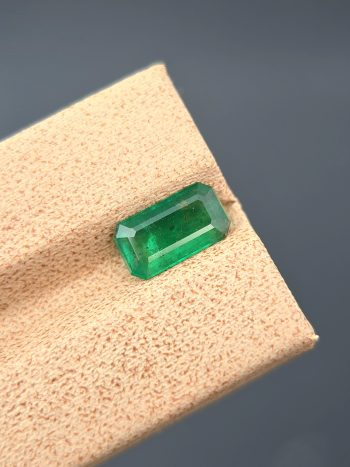 A crisp, detailed image of a 1.36 carat natural emerald from the Swat Valley, Pakistan. The stone is in the classic emerald cut and has a green color. Visible inclusions are present within the stone.