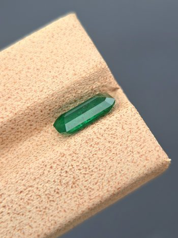 A crisp, detailed image of a 1.36 carat natural emerald from the Swat Valley, Pakistan. The stone is in the classic emerald cut and has a green color. Visible inclusions are present within the stone.