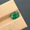 A clear, close-up photograph of a 1.18 carat natural emerald from Pakistan's Swat Valley. The stone is a cushion cut with a green color and visible internal inclusions.