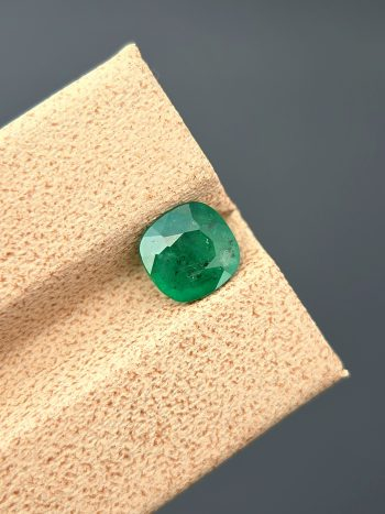A high-quality image of a 1.09 carat natural cushion-cut green emerald with visible inclusions, photographed against a neutral background. The gemstone is from the Swat Valley in Pakistan.