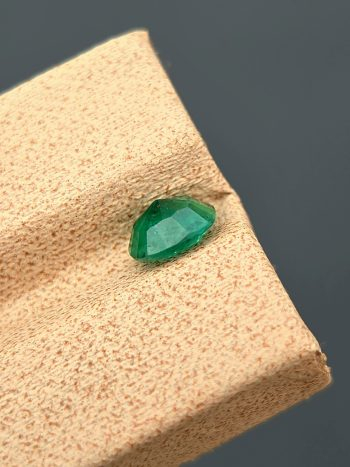 A high-quality image of a 1.09 carat natural cushion-cut green emerald with visible inclusions, photographed against a neutral background. The gemstone is from the Swat Valley in Pakistan.